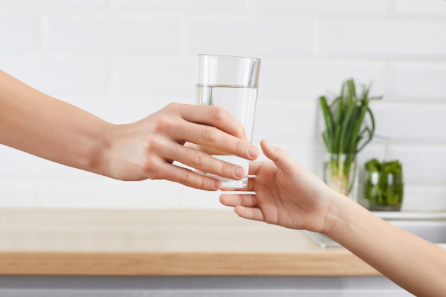 Hand giving water glass to child