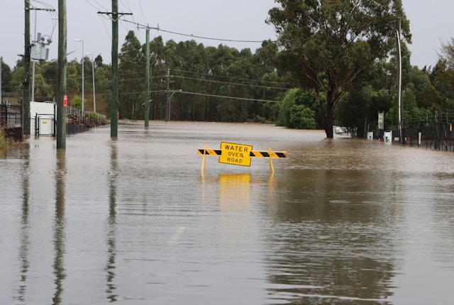Road flooded with a sign that reads "water over road"